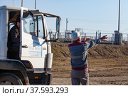 Aktobe region, Kazakhstan - May 04, 2019: Phosphate fertilizers plant. Loading station. Worker show direction for truck driver. Редакционное фото, фотограф Alexey Rezvykh / Фотобанк Лори