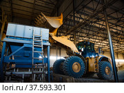 Phosphate fertilizers plant. Caterpillar excavator (bulldozer) loading raw materials (minerals) in machine hopper loader for processing. (2012 год). Редакционное фото, фотограф Alexey Rezvykh / Фотобанк Лори