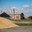 Grain storage. Straw haystacks right, wheat grain heap left. Brick grey building. Flying doves in air. Blue sky. Стоковое фото, фотограф Alexey Rezvykh / Фотобанк Лори