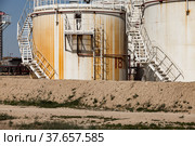 White and yellow oil storage tanks on bright sun on blue sky on oil refinery plant in desert. Стоковое фото, фотограф Alexey Rezvykh / Фотобанк Лори