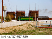 Brown rusted old oil storage tanks under bright sun on blue sky. Railway terminal of refinery plant in desert. Locomotive and carriages. Taraz city, Kazakhstan. Стоковое фото, фотограф Alexey Rezvykh / Фотобанк Лори