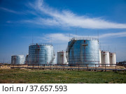 White and shiny metal oil storage tanks on bright sun. Oil refinery plant in desert.Against blue sky with light clouds. Panorama view. Near Taraz city, Kazakhstan. Стоковое фото, фотограф Alexey Rezvykh / Фотобанк Лори