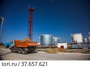 Jambyl region, Kazakhstan - April 25 2012: Oil Refinery and Gas processing plant storage. Steel storage tanks and orange dump truck with ground. Редакционное фото, фотограф Alexey Rezvykh / Фотобанк Лори