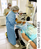 Ophthalmologist surgeon, together with assistants and nurse, performs complex operation to restore vision in a patient (2021 год). Редакционное фото, фотограф Евгений Ткачёв / Фотобанк Лори