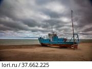 Kok-aral, Kazakhstan - 03 May, 2012: Small Aral sea Kok-aral sand dam. Fishing boat on the beach. Aral on horizon. Grey stormy clouds. Стоковое фото, фотограф Alexey Rezvykh / Фотобанк Лори