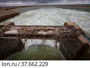 Small Aral Sea Kok-aral dam. Kazakhstan, Kyzylorda region. Concrete supports, metal shutters. turbulent water after dam.Grey storm sky. Стоковое фото, фотограф Alexey Rezvykh / Фотобанк Лори