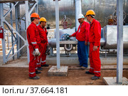 Kyzylorda region, Kazakhstan, May 01, 2012: Oil workers and engineer on refinery plant talking on heat exchanger background. Стоковое фото, фотограф Alexey Rezvykh / Фотобанк Лори