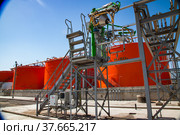 Orange steel storage tanks with acid at sulfuric (sulphuric) acid plant warehouse. Fire-extinguishing system. Kzylorda region, Kazakhstan. Стоковое фото, фотограф Alexey Rezvykh / Фотобанк Лори