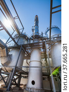 Sulphuric acid plant. Furnaces for sulfur burning for dioxide and smoking stack (factory chimney). Blue sky with sun background. Kzylorda region, Kazakhstan. Стоковое фото, фотограф Alexey Rezvykh / Фотобанк Лори
