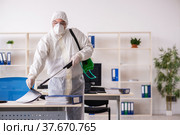 Old male contractor in office disinfection concept. Стоковое фото, фотограф Elnur / Фотобанк Лори