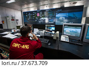 Oil refinery plant. Operation control center and operator in red work wear looks on monitors. CNPC company. (2012 год). Редакционное фото, фотограф Alexey Rezvykh / Фотобанк Лори