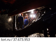 Khromtau, Aktobe region, Kazakhstan - May 06 2012: Gold ore mine underground gallery. Mining machine and engineers. Редакционное фото, фотограф Alexey Rezvykh / Фотобанк Лори