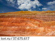 Aluminium ore quarry color layers. Bauxite clay open-cut mining. Texture of mineral cutting with excavator bucket. Blue sky with clouds background. Стоковое фото, фотограф Alexey Rezvykh / Фотобанк Лори