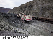 Rudny/Kazakhstan - May 14 2012: Open-pit mining iron ore in quarry. Excavator Terex loading ore in cargo train wagon. Редакционное фото, фотограф Alexey Rezvykh / Фотобанк Лори