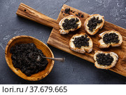 Sturgeon black caviar in wooden bowl and sandwiches on dark stone background. Стоковое фото, фотограф Лисовская Наталья / Фотобанк Лори