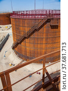 Rusted oil storage tanks on blue sky background. View from tank's roof. Asphaltic bitumen plant. Balustrade is out of focus. Стоковое фото, фотограф Alexey Rezvykh / Фотобанк Лори