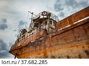 Mangystau, Kazakhstan - May 19, 2012: Bautino bay. Old rusted steel ship on Caspian Sea ship-repairing yard. Grey cloudy storm sky background. Close up photo. Стоковое фото, фотограф Alexey Rezvykh / Фотобанк Лори