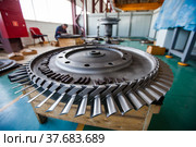 Atyrau,Kazakhstan-May 21,2012: Service of steam turbines in Kazturboremont (KTR) plant. Close-up of turbine rotor (impeller) Changing blades. Worker in workshop interior, blurred. Стоковое фото, фотограф Alexey Rezvykh / Фотобанк Лори