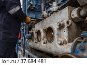 Uralsk region, Kazakhstan - May 24 2012: Oil deposit Zhaikmunai. Serviceman worker fixing mud pump engine. Baker Hughes company. Close-up, no face. Редакционное фото, фотограф Alexey Rezvykh / Фотобанк Лори