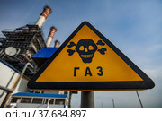 Modern gas power station. Yellow triangle dangerous warning sign. Title on sign: Gas. Smocking stacks on blue sky. Uralsk city, Kazakhstan. Стоковое фото, фотограф Alexey Rezvykh / Фотобанк Лори