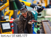 Ekibastuz, Pavlodar region, Kazakhstan - May 28 2012: Train car-building plant. Gas-burner welding wagon parts. Young welder in protective mask. Редакционное фото, фотограф Alexey Rezvykh / Фотобанк Лори