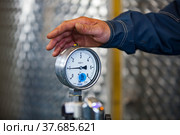 Ekibastuz, Kazakhstan - May 28, 2012. Explosive material production plant for coal quarry mining. Manometer gauge and worker's hand. Close up. Стоковое фото, фотограф Alexey Rezvykh / Фотобанк Лори