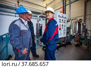 Ekibastuz, Kazakhstan - May 28, 2012. Explosive material production plant for coal quarry mining. Group of engineers talking. Equipment on background. Редакционное фото, фотограф Alexey Rezvykh / Фотобанк Лори