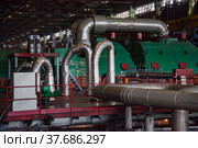 Aksu, Pavlodar region, Kazakhstan - May 29, 2012: Aksu steam power station workshop. Green electric machine, steam turbine and generator. Pipes with thermal insulation and shiny metal cover. Редакционное фото, фотограф Alexey Rezvykh / Фотобанк Лори