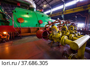 Aksu, Pavlodar region, Kazakhstan - May 29, 2012: Aksu steam power station workshop. Close up photo of vintage valves of extinguisher system. Steam turbine with electric machine on background. Редакционное фото, фотограф Alexey Rezvykh / Фотобанк Лори
