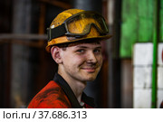 Aksu, Pavlodar region, Kazakhstan - May 29, 2012: Aksu steam power station. Portrait of young caucasian worker with dirty face in yellow hardhat. Close up photo. Blurred background. Редакционное фото, фотограф Alexey Rezvykh / Фотобанк Лори