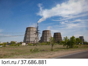 Pavlodar thermal electric station. Cooling towers and smoke stack with white smoke. Blue sky. Green grass, trees. Asphalt road right. Стоковое фото, фотограф Alexey Rezvykh / Фотобанк Лори