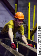 Temirtau, Kazakhstan - June 09, 2012: Concrete sleepers manufacturing plant NORD Prom NS. Portrait of young smiling Asian worker. Редакционное фото, фотограф Alexey Rezvykh / Фотобанк Лори