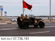 Мужчины в военной форме времен ВОВ, на автомобиле ГАЗ-67, с красным знаменем, на дороге Нижнего Новгорода (2022 год). Редакционное фото, фотограф Nikolay Pestov / Фотобанк Лори