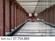 Moscow Russia - may 07 2022: View of the cafe at the end of the gallery with brick columns. Sunlight shines from the side and the shadow of the columns falls on the floor. Редакционное фото, фотограф Yuriy Savin / Фотобанк Лори