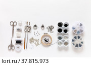Flat lay of process of embroidering a broach in form of black and white symbol of yin and yang with beads, bugle, rhinestones and gimp. Tools and sets of beads on white background. Fashion hobby. Copy space. Стоковое фото, фотограф Виктория Катьянова / Фотобанк Лори