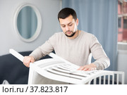 Young man wiping chair with duster at home. Стоковое фото, фотограф Яков Филимонов / Фотобанк Лори