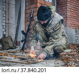 Солдат разводит костёр в разрушенном здании. Военный разжигает огонь для приготовления еды. (2021 год). Редакционное фото, фотограф Виталий Михайлюк / Фотобанк Лори