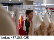 Женщина выбирает платье в pop-up магазине российских дизайнеров в магазине в ЦУМе города Москвы, Россия (2022 год). Редакционное фото, фотограф Николай Винокуров / Фотобанк Лори