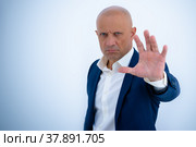 Мужчина в деловом костюме поднял руку и запрещает проход. Жест остановки. Стоковое фото, фотограф Виталий Михайлюк / Фотобанк Лори