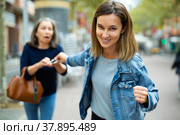 Woman thief trying to snatch smartphone from elderly woman outdoors. Стоковое фото, фотограф Яков Филимонов / Фотобанк Лори