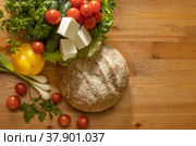 Bread with fresh vegetables, cherry tomatoes, cucumbers, bell peppers, onions, parsley and cheese cheese lying on a wooden table. Стоковое фото, фотограф Диана Гарифуллина / Фотобанк Лори