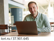 Young businessman sitting in cafe working with laptop computer. Стоковое фото, фотограф Сергей Толмачёв / Фотобанк Лори