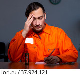 Young convict man sitting in dark room. Стоковое фото, фотограф Elnur / Фотобанк Лори