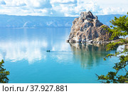 Magnificent summer landscape with Baikal Lake on a sunny day. Tourists travel in a rubber boat around the famous Shaman Rock. Flocks of June midges are visible on water. Natural background. Стоковое фото, фотограф Виктория Катьянова / Фотобанк Лори