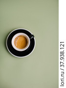 Delicious hot espresso with a beautiful thick crema in a ceramic black cup with a saucer standing on the green background. Стоковое фото, фотограф Анастасия Белоусова / Фотобанк Лори