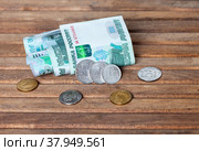 Russian rubles. Several ruble coins of different denominations and 1000 ruble paper banknotes rolled up on wooden background. Concept of Russian economy, foreign investment, business, banking system and inflation. Стоковое фото, фотограф Виктория Катьянова / Фотобанк Лори
