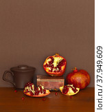 A beautiful still life with ripe pomegranates, a clay cup of garnet juice and a stone box made of rhodonite on wooden table. Foreground. Empty space on top on brown background. Vintage style. Стоковое фото, фотограф Виктория Катьянова / Фотобанк Лори