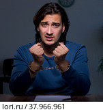 Young convict man sitting in dark room. Стоковое фото, фотограф Elnur / Фотобанк Лори