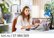 Concentrated young businesswoman working with laptop and papers in office. Стоковое фото, фотограф Яков Филимонов / Фотобанк Лори