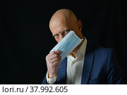Мужчина закрывает рот медицинской маской. Стоковое фото, фотограф Виталий Михайлюк / Фотобанк Лори